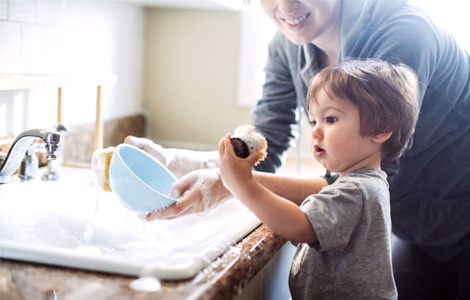 Small child helping mom wash dishes