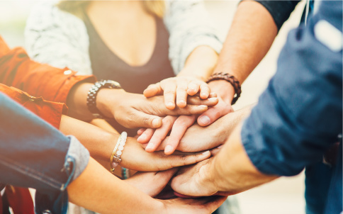 A circle of people have put their hands in as a team.