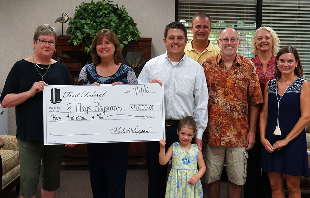 Leaders from the 8 Flags playscapes smile after receiving their check from First Federal's Community Rewards Program.