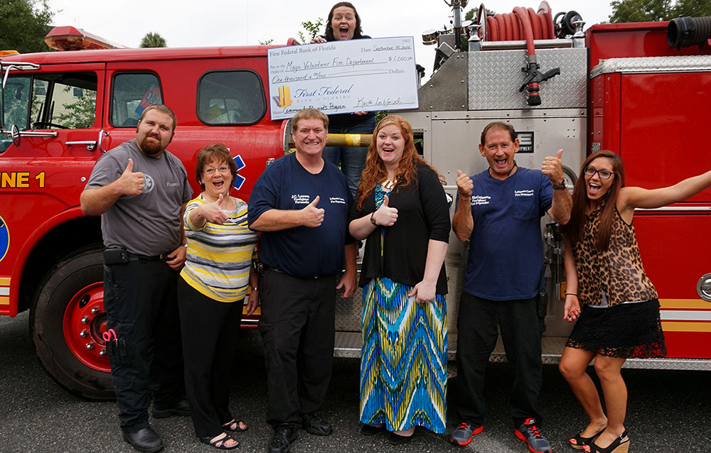Members of the Lafayette County volunteer fire department stand in front of one of their fire engines after receiving their check.