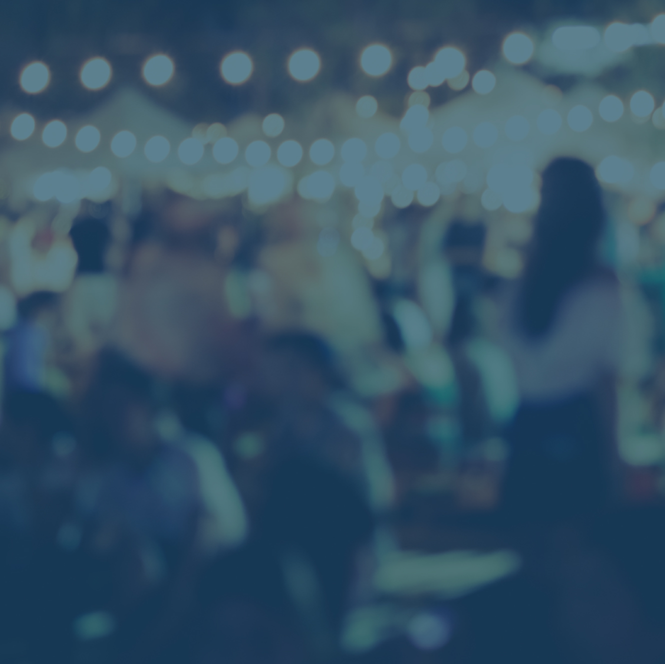 A blurry scene of a gathering of people under party lights.