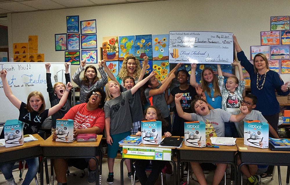 Students from Suwannee Primary school raise their hands in excitement after receiving their check.