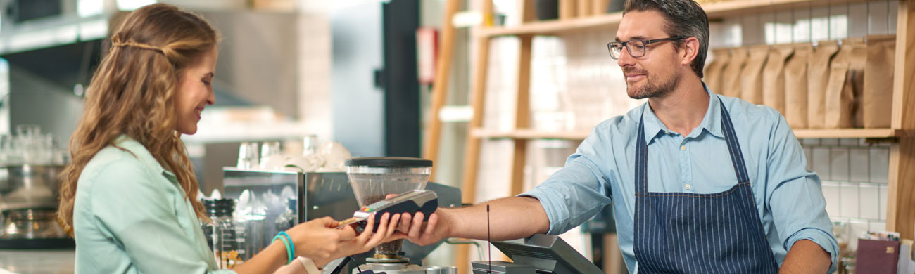 Customer in coffee shop pays for her purchase.