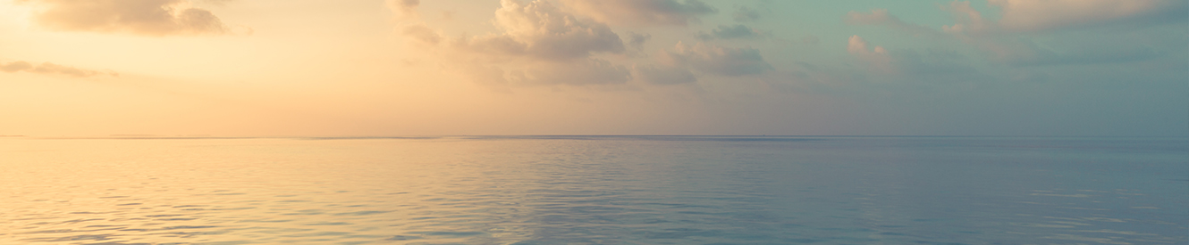 A orange sky over a smooth ocean at dusk.