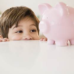 A young boy peering at a piggy bank