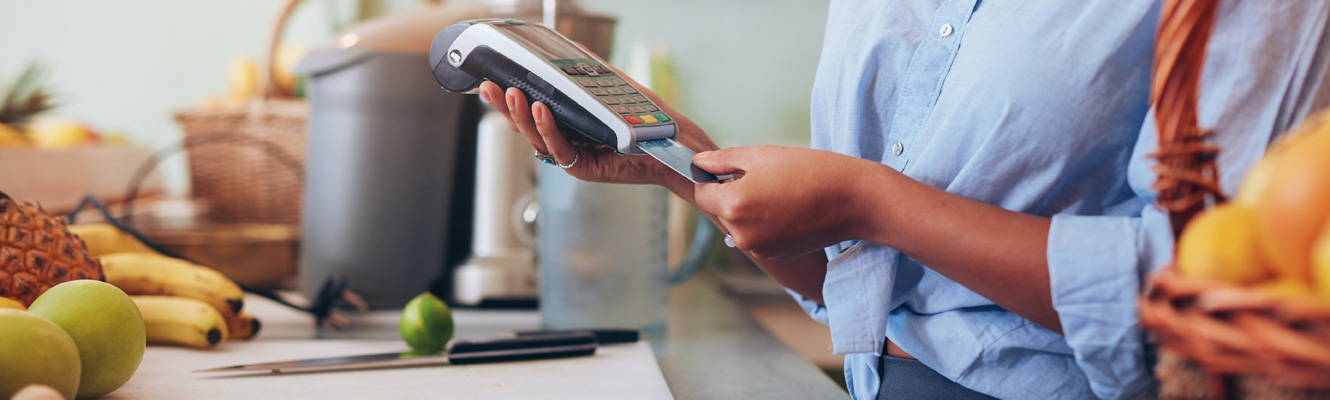 A woman in a juice shop swipes a credit card for a customer to complete a transaction.