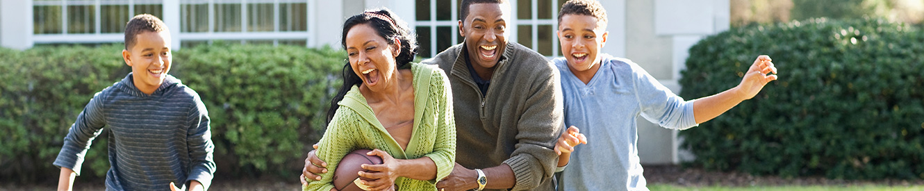 A happy family plays football in their back yard.