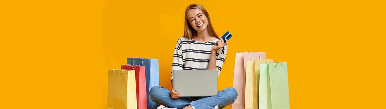 A young woman holds a debit card with gift bags on either side of her