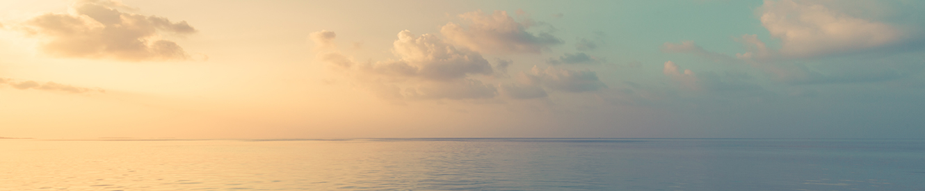 A orange sky over a smooth ocean at dusk.