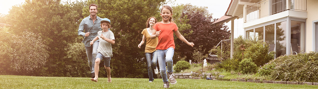 A happy family runs through the yard in front of their home.